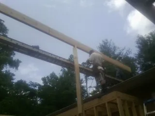 Carpenter setting a ridge beam over a new addition frame — Ice Dam Removal by Roofing Brothers in Millington