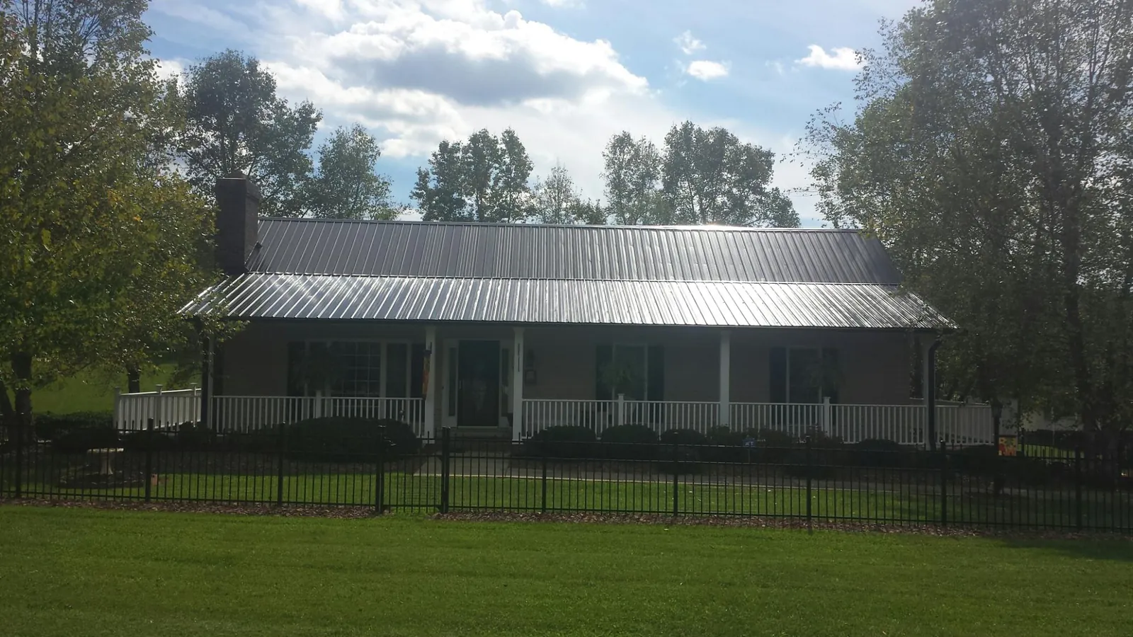 Gray metal roof on a brick ranch with a full width front porch — Gutter Guard Installation work by our crew in Millington