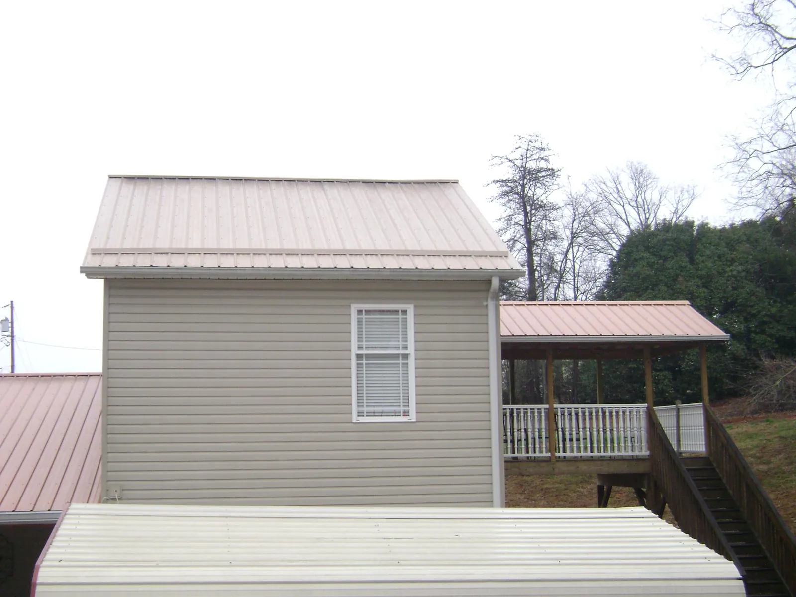 Tan metal roofs on a two story addition and attached porch, from a Roof Replacement job in Millington